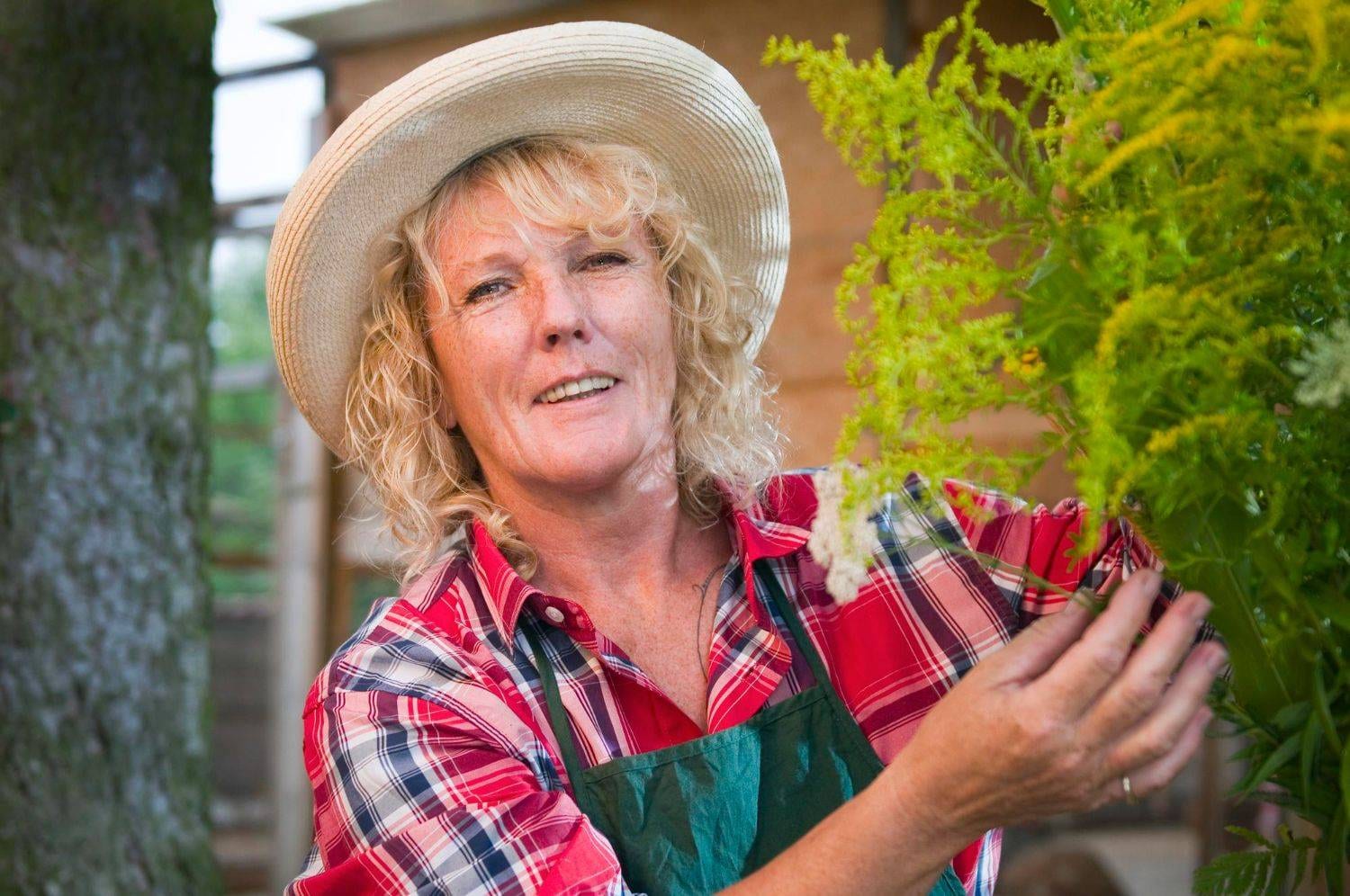 portrait of woman wearing hat while touching plant