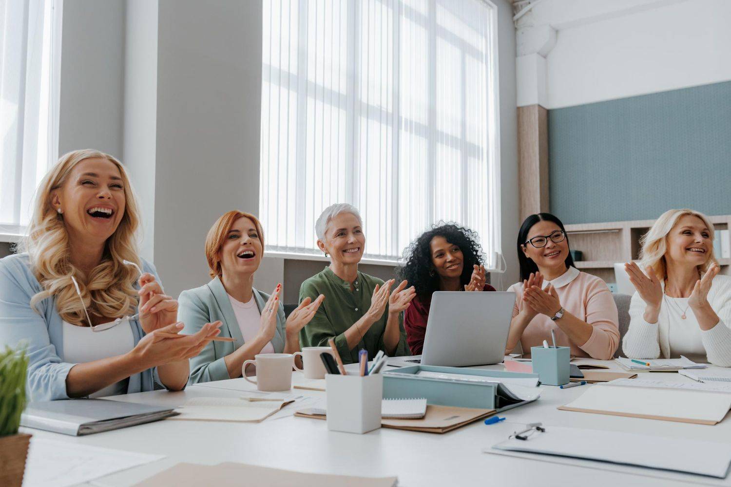 group of happy businesswomen applauding while having meeting in the office