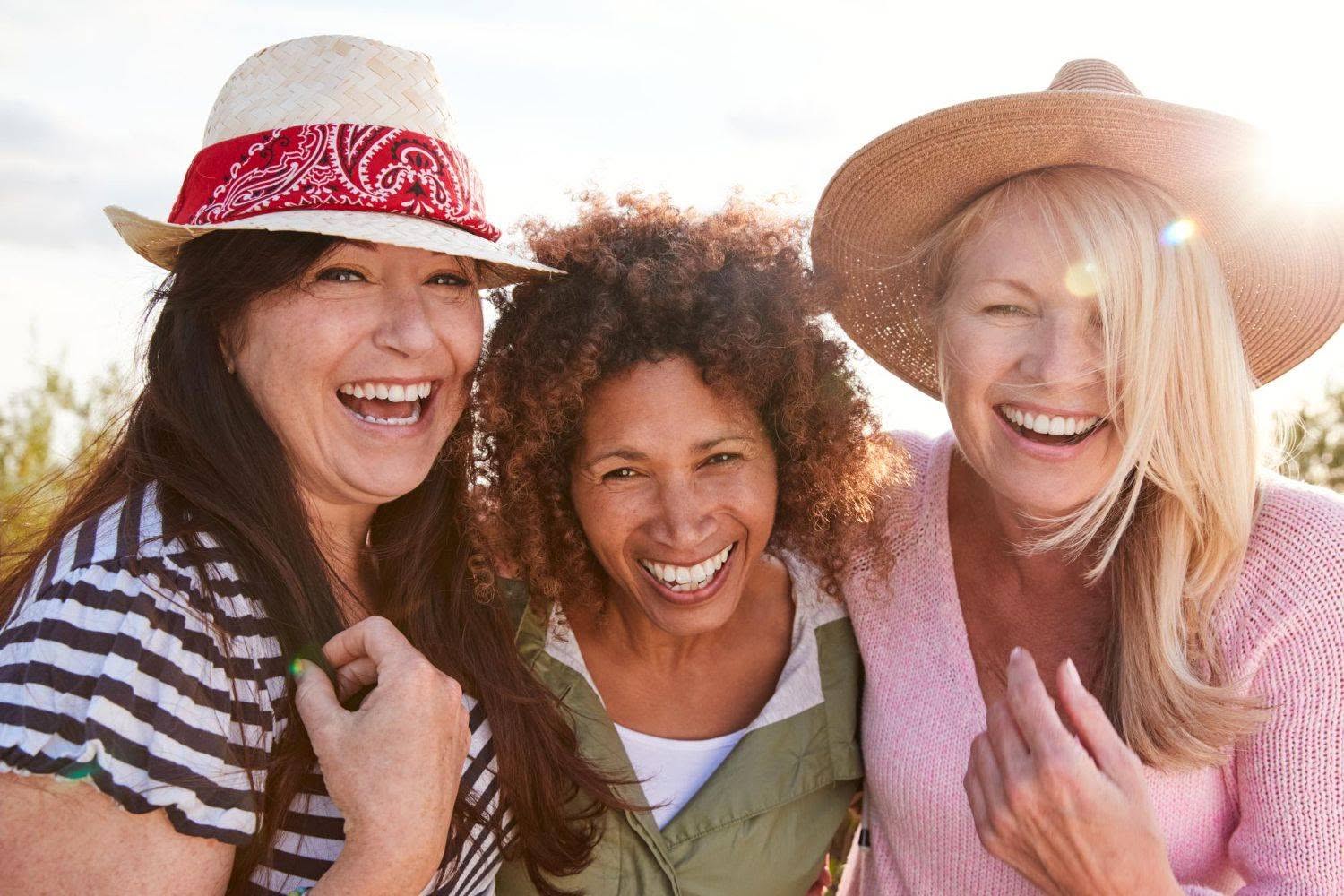 portrait of mature female friends walking through field on camping vacation (1500x1000)