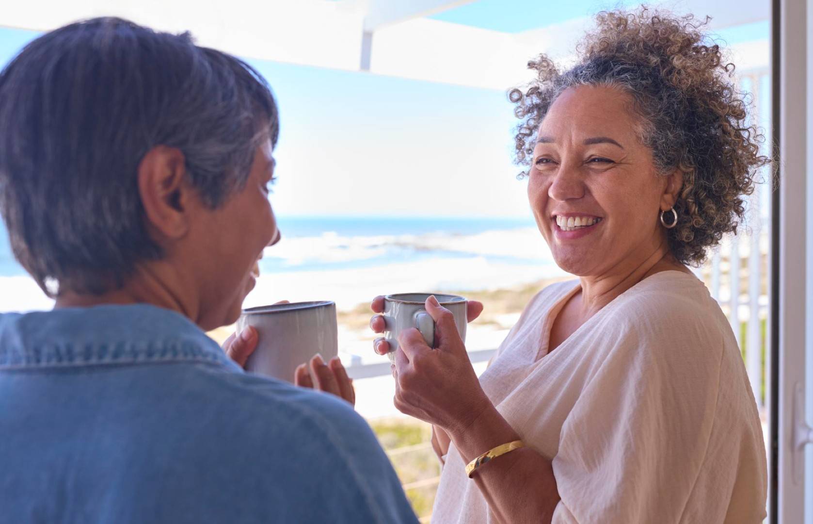 two mature women friends in beachfront house overlooking ocean (large)